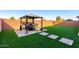 Backyard featuring a patio set beneath a gazebo like structure and synthetic grass at 25627 N 163Rd Dr, Surprise, AZ 85387