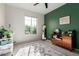 Bright bedroom featuring a large window, carpeted floor, and green accent wall at 25627 N 163Rd Dr, Surprise, AZ 85387