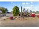 Inviting single-story home featuring a well-manicured front yard with mature trees and colorful flowering bushes at 2616 E Des Moines St, Mesa, AZ 85213