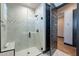Walk-in shower with white tile and glass doors with a black door to the hallway at 26689 W Ponderosa Ln, Buckeye, AZ 85396