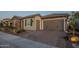 Charming home exterior showcasing a three-car garage, stone accents, desert landscaping, and paved driveway at 26689 W Ponderosa Ln, Buckeye, AZ 85396