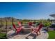 Backyard with a charming fire pit area surrounded by comfortable Adirondack chairs at 26689 W Ponderosa Ln, Buckeye, AZ 85396