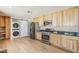 Kitchen featuring modern appliances, wood cabinets, and stacked laundry at 3138 N 82Nd Pl, Scottsdale, AZ 85251