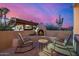 Charming outdoor space with a cozy fireplace, comfortable rocking chairs, and scenic desert views at 3333 N 87Th St, Mesa, AZ 85207