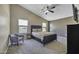 Spacious bedroom with plush carpet, windows, ceiling fan, and accent chair at 40845 W Thornberry Ln, Maricopa, AZ 85138
