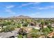 Stunning aerial view of a neighborhood with mature trees, well-maintained homes, and Camelback Mountain in the distance at 4645 E Cambridge Ave, Phoenix, AZ 85008