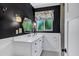 Chic bathroom with black walls, floral window coverings, and a white vanity with marble countertop and mirror at 4645 E Cambridge Ave, Phoenix, AZ 85008