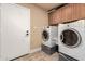 Laundry room with modern washer and dryer units, tiled floors, and storage cabinets at 5616 E Desert Vista Trl, Cave Creek, AZ 85331