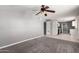 Spacious gray carpeted living room featuring a ceiling fan and seamless flow into the kitchen area at 6033 S 19Th Pl, Phoenix, AZ 85042