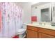 Cozy bathroom with a floral shower curtain and a wooden vanity with a single sink at 6528 S 258Th Dr, Buckeye, AZ 85326