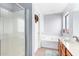 Bright bathroom featuring a walk-in shower, soaking tub, and single sink vanity at 6528 S 258Th Dr, Buckeye, AZ 85326