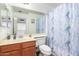 Well-lit bathroom with a wood vanity and a shower with a stylish marble-patterned curtain at 6528 S 258Th Dr, Buckeye, AZ 85326
