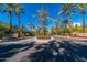 Community entrance featuring lush landscaping, flowering plants, and towering palm trees at 7272 E Gainey Ranch Rd # 121, Scottsdale, AZ 85258