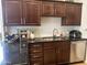 Close-up of kitchen with dark wood cabinetry, granite countertops, and stainless steel appliances at 7272 E Gainey Ranch Rd # 121, Scottsdale, AZ 85258