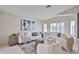 Bright living room featuring white sofas, modern art, and neutral decor with natural light from shuttered windows at 7633 W Kristal Way, Glendale, AZ 85308