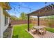 Inviting backyard patio with artificial grass, dining set, and pergola with string lights for outdoor gatherings at 16498 W Gary Way, Goodyear, AZ 85338