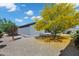 Charming gray home with a beautifully landscaped backyard, featuring a vibrant yellow tree and desert landscaping at 35733 W Santa Monica Ave, Maricopa, AZ 85138