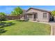 Well-kept backyard showcasing green grass, a covered patio, and a brick perimeter wall for privacy at 15391 W Yucatan Dr, Surprise, AZ 85379