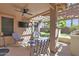 Relaxing covered patio with a ceiling fan, a mounted TV, comfortable seating, and access to a well-maintained yard at 15391 W Yucatan Dr, Surprise, AZ 85379