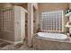 Luxurious bathroom featuring a soaking tub, glass block window, and tiled accents at 22635 N 54Th Pl, Phoenix, AZ 85054