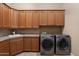 Bright laundry room with custom wood cabinets, tile backsplash, sink, and high-end washer and dryer at 22635 N 54Th Pl, Phoenix, AZ 85054
