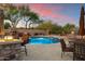 Inviting outdoor pool area featuring a fireplace, lounge chairs, and lush desert landscaping at 22635 N 54Th Pl, Phoenix, AZ 85054