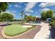 Backyard features pool, outdoor kitchen, putting green, sport court, mature trees, flowers and blue sky at 3356 E Vallejo Ct, Gilbert, AZ 85298