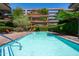 Inviting community pool with lounge chairs and umbrellas, surrounded by lush greenery and a modern residential building at 7131 E Rancho Vista Dr # 1008, Scottsdale, AZ 85251