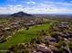 Aerial view showcasing lush golf course and community nestled against mountain backdrop at 7445 E Eagle Crest Dr # 1015, Mesa, AZ 85207