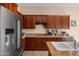 Charming kitchen with stainless steel refrigerator, wood cabinets, granite countertops, and tile floors at 7445 E Eagle Crest Dr # 1015, Mesa, AZ 85207