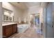 Bright main bathroom with double vanity, soaking tub, tiled floors, and walk-in closet at 7445 E Eagle Crest Dr # 1015, Mesa, AZ 85207