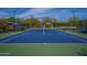 Well-maintained community tennis court with a green and blue surface and a shaded bench for players at 7445 E Eagle Crest Dr # 1015, Mesa, AZ 85207
