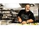 Personal in chef's attire smiles while chopping vegetables in a commercial kitchen at 12940 W Creosote Dr, Peoria, AZ 85383