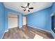 Bedroom with wood-look floors, closet, neutral walls, and a ceiling fan for comfortable living at 13676 N 73Rd Dr, Peoria, AZ 85381