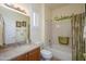 Bright bathroom featuring a vanity with light counter, shuttered window, and bathtub with leaf-patterned curtain at 17234 W Calistoga Dr, Surprise, AZ 85387