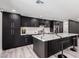 Stylish kitchen showcasing dark cabinets, quartz countertops, island with bar seating, and stainless appliances at 3008 W Michigan Ave, Phoenix, AZ 85053