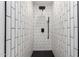 This tiled shower features a sleek black shower head and black accents at 3008 W Michigan Ave, Phoenix, AZ 85053