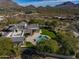 An aerial shot showing the home, lush green backyard, pool, deck, and surrounding desert landscape with mountain views at 10160 E Whispering Wind Dr, Scottsdale, AZ 85255