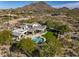 Expansive property with a luxurious pool, lush green lawn, and impressive architecture nestled within a desert landscape at 10160 E Whispering Wind Dr, Scottsdale, AZ 85255