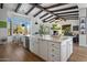 Gourmet kitchen with island, farmhouse sink, beamed ceilings, and open layout to the living area with fireplace at 10160 E Whispering Wind Dr, Scottsdale, AZ 85255