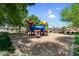 Colorful playground equipment in a community park with mature shade trees at 11225 E Sylvan Ave, Mesa, AZ 85212
