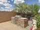 Outdoor kitchen featuring a stone surround, stainless steel grill, and mature landscaping at 1350 E Racine Dr, Casa Grande, AZ 85122