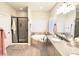 Bright bathroom with soaking tub, glass enclosed shower, granite counters, and light wood look floors at 1421 W Rylie Ct, Queen Creek, AZ 85144
