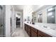 Bathroom featuring double vanity, large mirror, tiled flooring, and a walk-in closet at 14637 W Wethersfield Rd, Surprise, AZ 85379