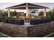 Covered outdoor patio with dining tables and chairs, surrounded by lush landscaping and houses at 17160 W Montpelier St, Surprise, AZ 85388