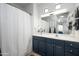 Well-lit bathroom featuring a navy vanity, a bathtub with curtain, and neutral tile at 19777 N 76Th St # 3229, Scottsdale, AZ 85255