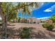 Exterior of property showcasing desert landscaping, mature trees, and a three-car garage at 21615 E Pegasus Pkwy, Queen Creek, AZ 85142