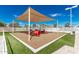 Community playground with soft turf, shade canopy, and varied play equipment for active  at 2239 S Cottonwood --, Mesa, AZ 85202