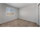A well-lit bedroom featuring neutral carpet, white walls, and a window with views of the outdoors at 2428 S 246Th Ln, Buckeye, AZ 85326
