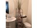 Powder room features a pedestal sink, round mirror, storage rack, and neutral decor at 2665 E Gillcrest Rd, Gilbert, AZ 85298